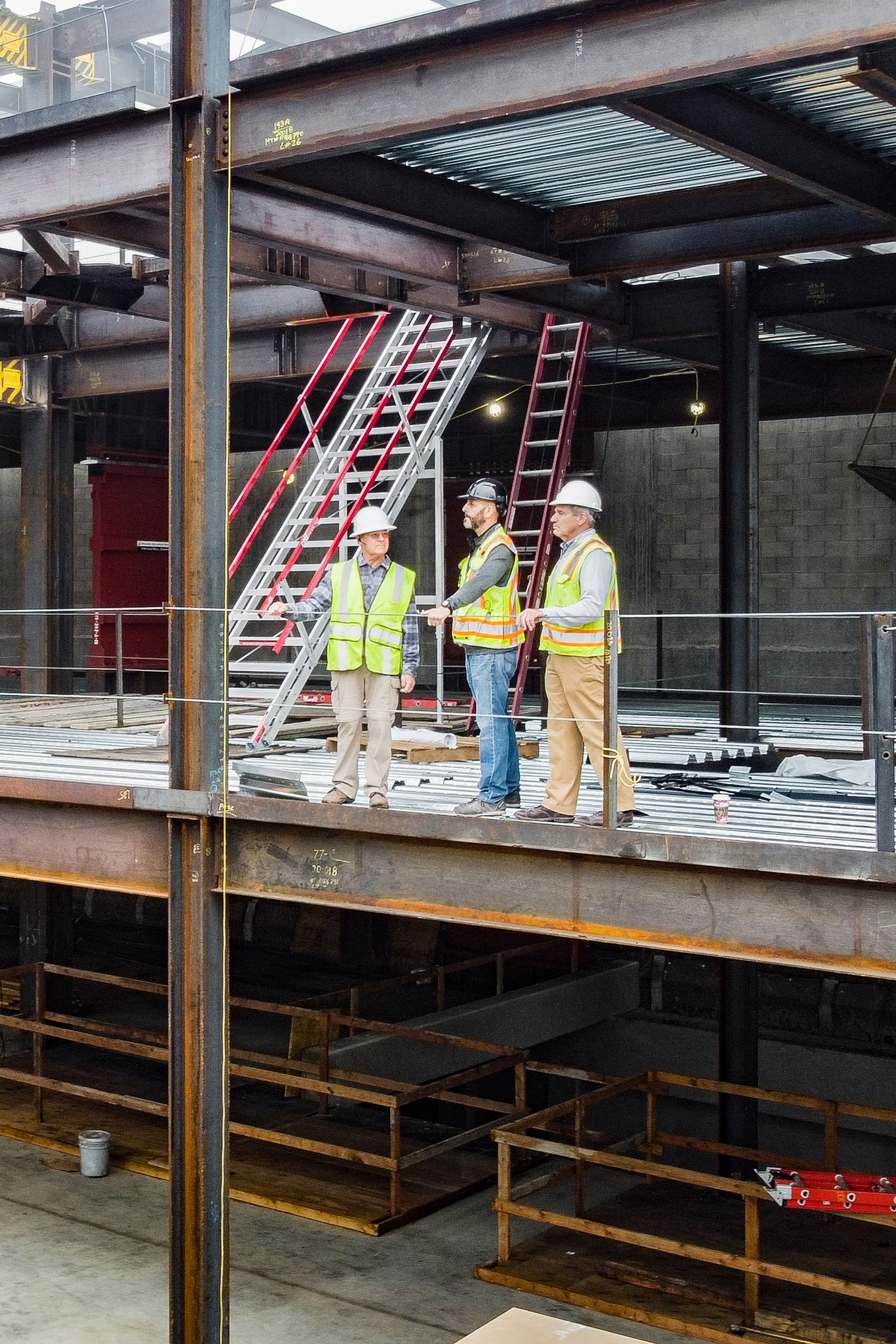 Construction team overlooks job site from 2nd floor steel structure